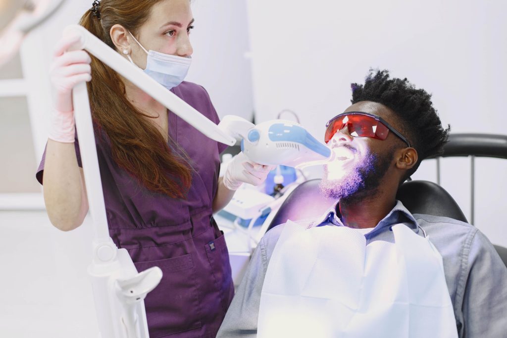 A man receiving teeth whitening from a dental professional